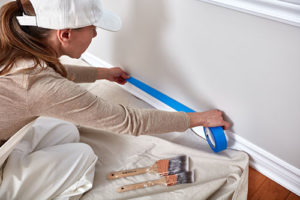 Painting Prep Affecting Residential Painting Cost - Woman Applying Painter's Tape to Trim